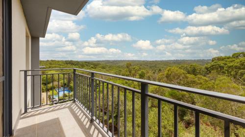 a balcony with a view of the woods at Oaks Sydney North Ryde Suites in Sydney