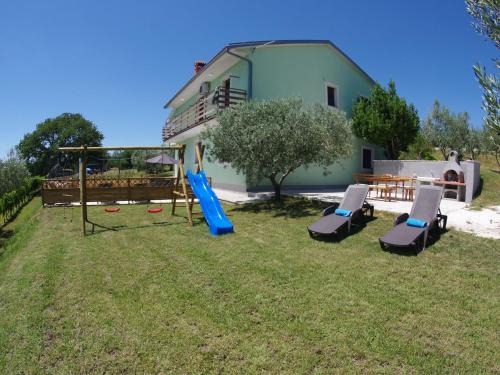 Gorica的住宿－Spacious apartment with views of the vineyards，一座带滑梯和椅子的游乐场的房子