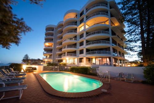 a hotel with a swimming pool in front of a building at Albatross North Apartments in Gold Coast