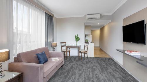 a living room with a couch and a table at Oaks Sydney North Ryde Suites in Sydney