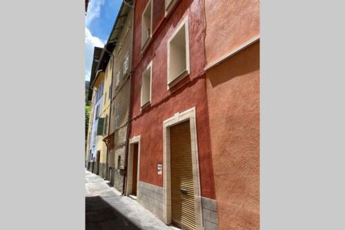 an alley with a red brick building with a door at 2 Pièces La Tour in Saint-Étienne-de-Tinée