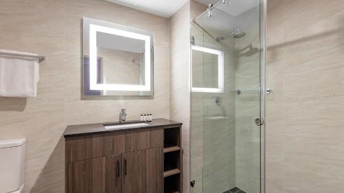 a bathroom with a sink and a glass shower at Oaks Sydney North Ryde Suites in Sydney