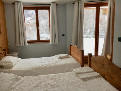 two beds in a room with two windows at Chalet Rivière, 5 en-suite. in La Salle Les Alpes