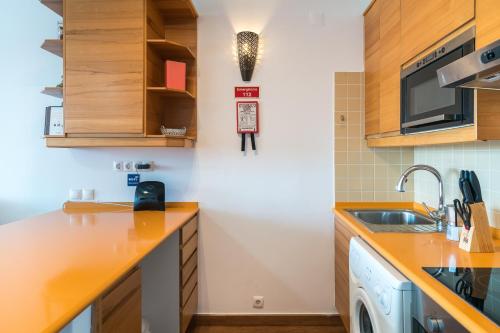 a kitchen with wooden cabinets and a sink at *AlgarvianStudio-Vilamoura City Centre* in Vilamoura