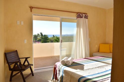 a bedroom with a bed and a window and a chair at Villa Bonobo in Puerto Escondido