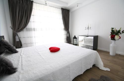 a bedroom with a white bed with a red pillow on it at Casa Bella in Ştefăneştii de Jos