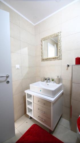 a white bathroom with a sink and a mirror at Casa Bella in Ştefăneştii de Jos