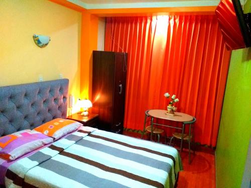 1 dormitorio con cama, mesa y cortinas en Sombrero de Paja en Chiclayo