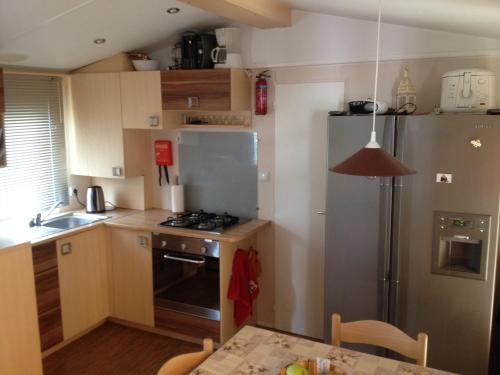 a kitchen with a stainless steel refrigerator and a table at Magic Mobile Montourey, 3 chambres, 2 salles de bain, piscine disponible sur place in Fréjus