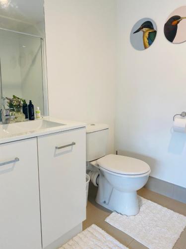 a white bathroom with a toilet and a sink at Takapuna Guest House in Auckland