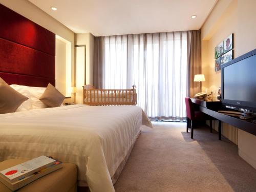 pokój hotelowy z łóżkiem i telewizorem z płaskim ekranem w obiekcie Howard Johnson Parkland Hotel Dalian w mieście Dalian