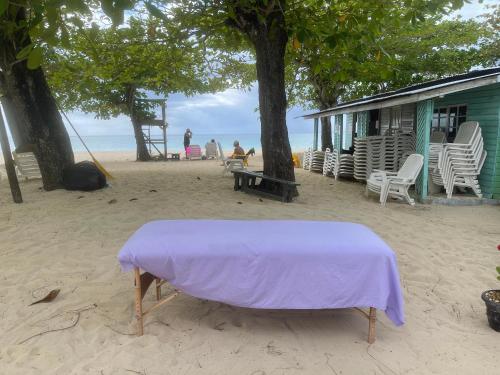 a table on the beach with a purple blanket on it at Marriott White Sands, BeachFront Condo at Negril Beach Club in Negril