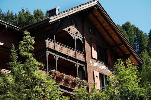 a large wooden building with a balcony at Hotel Sonnenhalde, Arosa in Arosa