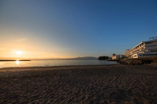 a beach with the sun setting over the water at Ibusuki Kaijo Hotel in Ibusuki