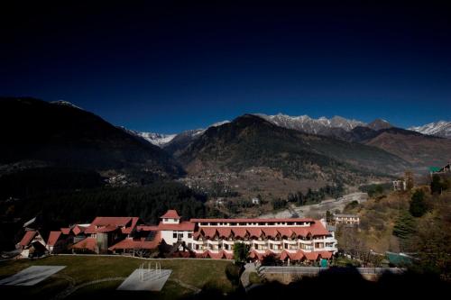 a resort in a valley with mountains in the background at Manuallaya The Resort & Spa in Manāli