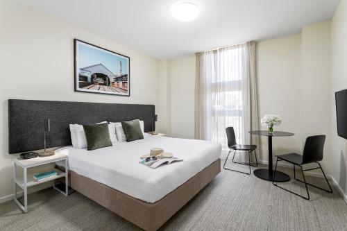 a hotel room with a large bed and a table at Quest Ballarat in Ballarat