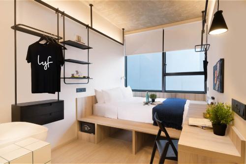 a bedroom with a white bed and a desk and a table at lyf Funan Singapore in Singapore