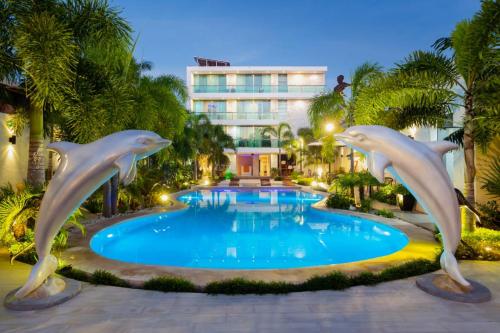 una piscina con estatuas de delfines frente a un hotel en Hotel & Suites Country, en Valladolid