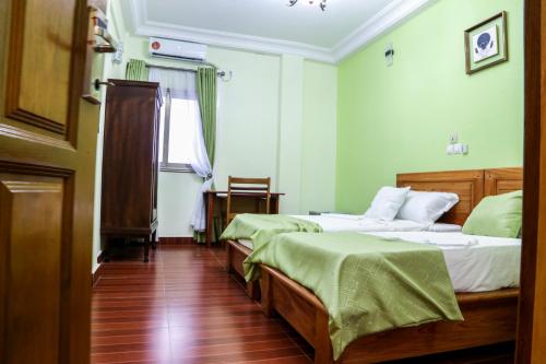Habitación con 2 camas, paredes verdes y suelo de madera. en Hôtel Libertis en Duala