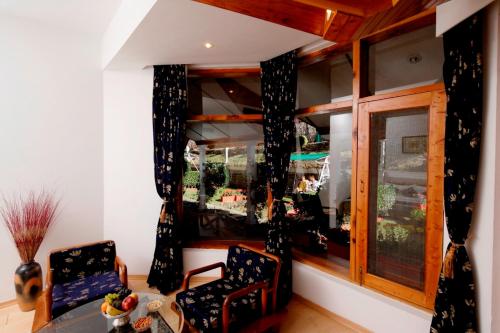 a room with two chairs and a window at Manuallaya The Resort & Spa in Manāli