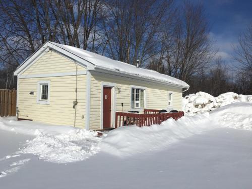 a small white house with a red door in the snow at Lakeshore Suites in North Bay