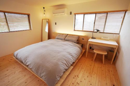 a bedroom with a bed and a desk and windows at ta bi to〈旅人〉 in Goto