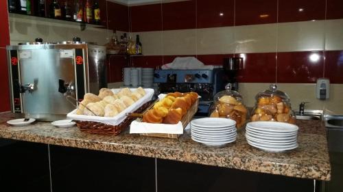 un bancone con piatti, pasticcini e pane sopra di Residencial Pinto a Guarda