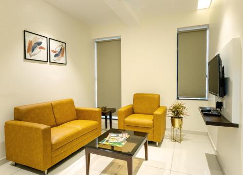 a living room with two chairs and a tv at Hotel Paramount Suites & Service Apartments in Mangalore