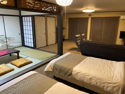 1 dormitorio con 2 camas, mesa y sofá en お宿 勝, en Nagiso