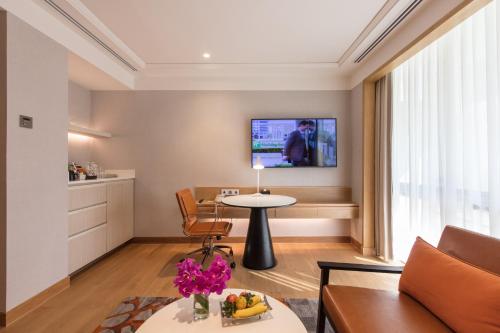 a living room with a table and a tv on the wall at Holiday Inn Bangkok by IHG in Bangkok