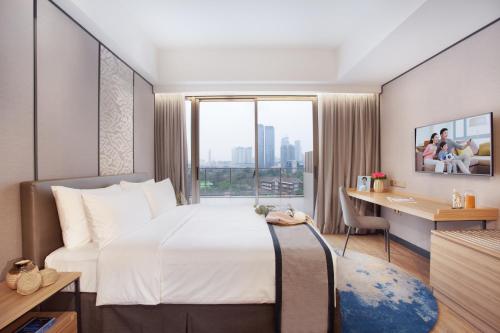 a hotel room with a bed and a desk and a window at Somerset Sudirman Jakarta in Jakarta