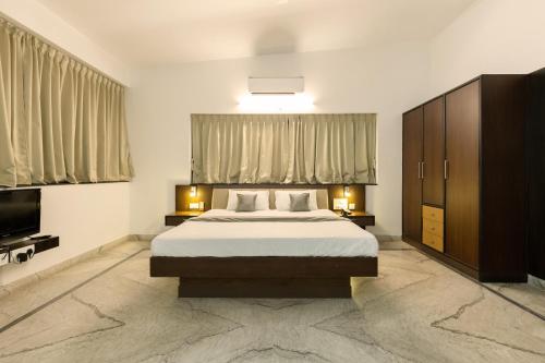 a bedroom with a large bed and a television at Hotel Paramount Suites & Service Apartments in Mangalore