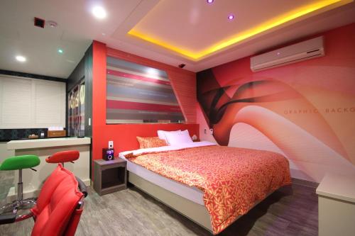 a bedroom with a bed and a red wall at Vov Hotel in Busan