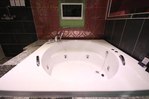 a white bath tub in a bathroom with a mirror at Vov Hotel in Busan