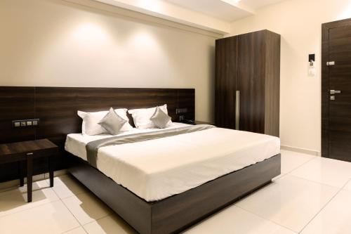 a bedroom with a large bed with a wooden headboard at Hotel Paramount Suites & Service Apartments in Mangalore