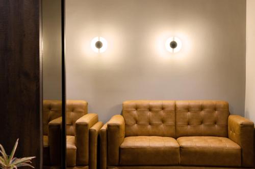 a waiting room with a brown leather couch and mirrors at Hotel Paramount Suites & Service Apartments in Mangalore
