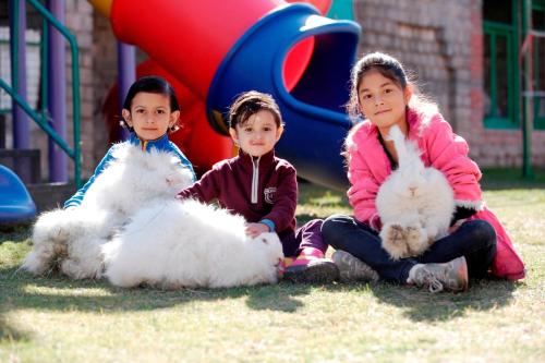 three children sitting on the grass with their animals at Manuallaya The Resort & Spa in Manāli