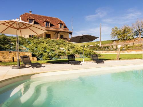 una piscina con due sedie e ombrelloni di Luxury villa with pool on the edge of Montignac a Montignac