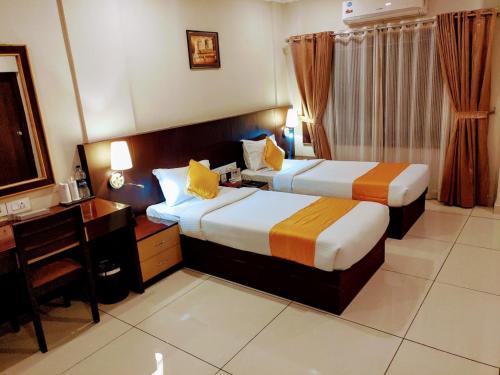 a hotel room with two beds and a desk at Hotel Virad in Kottakkal