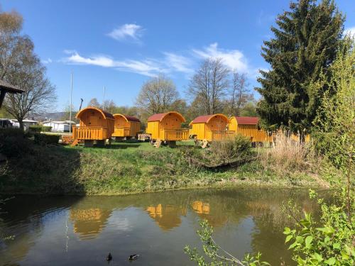 un groupe de petites maisons près d'une rivière dans l'établissement NATURAMA BEILNGRIES - SchäferwagenDorf, à Beilngries