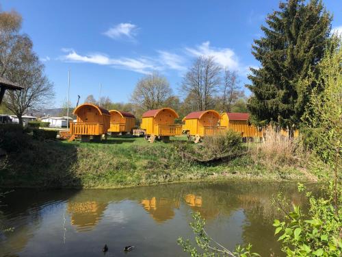 un gruppo di piccole case vicino a un fiume di NATURAMA BEILNGRIES - SchäferwagenDorf a Beilngries