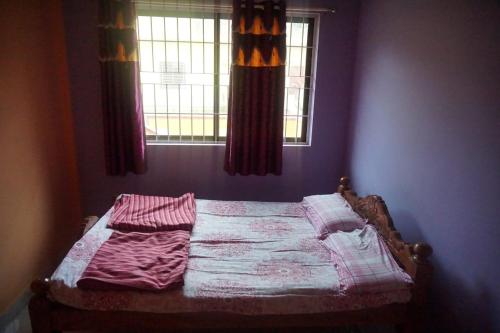 an unmade bed in a bedroom with a window at Vamoose Balgal Homestay in Kalasa