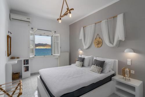 a white bedroom with a bed and a window at Venia's Guesthouse in Pollonia