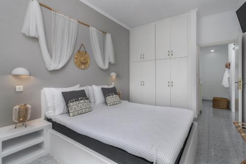 a white bedroom with a bed with white cabinets at Venia's Guesthouse in Pollonia