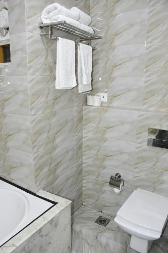 a bathroom with a toilet and a sink and towels at HOTEL ANAND INTERNATIONAL in Bodh Gaya