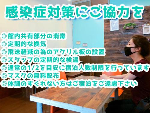a woman wearing a face mask sitting at a table at Guest House Cam Cam Okinawa in Naha