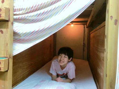 a young child laying on a bed in a play house at Guest House Cam Cam Okinawa in Naha