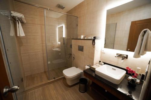 a bathroom with a toilet and a sink and a shower at Hotel Le Amritam in Dehradun