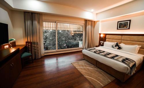 ein Schlafzimmer mit einem großen Bett und einem großen Fenster in der Unterkunft Hotel Le Amritam in Dehradun