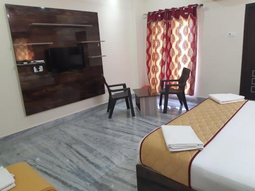 a hotel room with a bed and two chairs and a tv at Devansh Bhanu Residency DBR in Srikalahasti